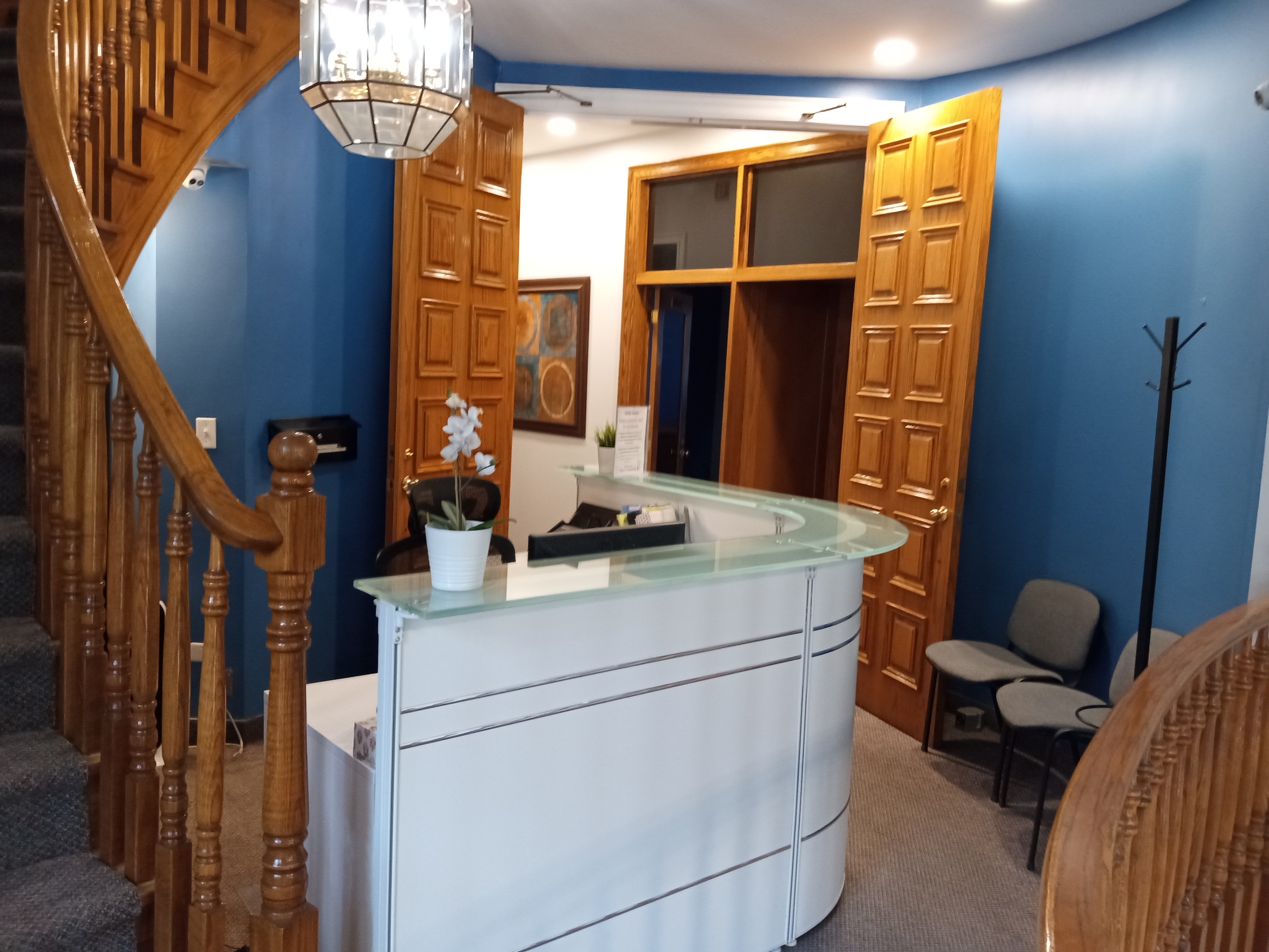Interior view of the IMG Ultrasound Training Hub reception area featuring a modern front desk, wooden staircase, blue walls, and seating arrangements.